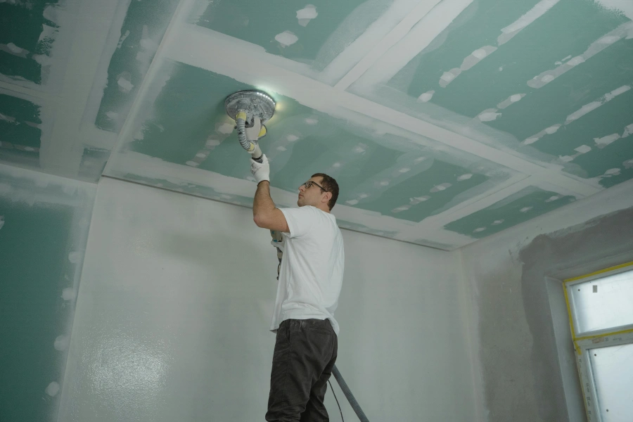 A worker installing a gypsum ceiling panel