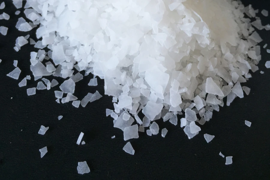 White flake magnesium chloride placed on a black background.