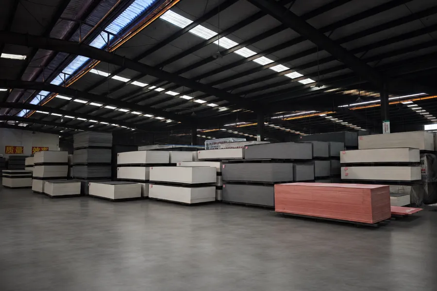 Interior view of a magnesium oxide board factory warehouse showing stacked finished MgO boards, organized storage, and large-scale manufacturing operations.